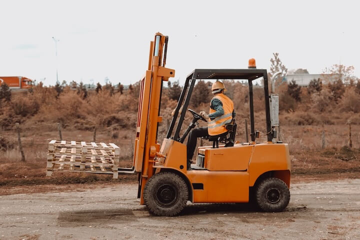 worker carrying empty pallets using forklift
