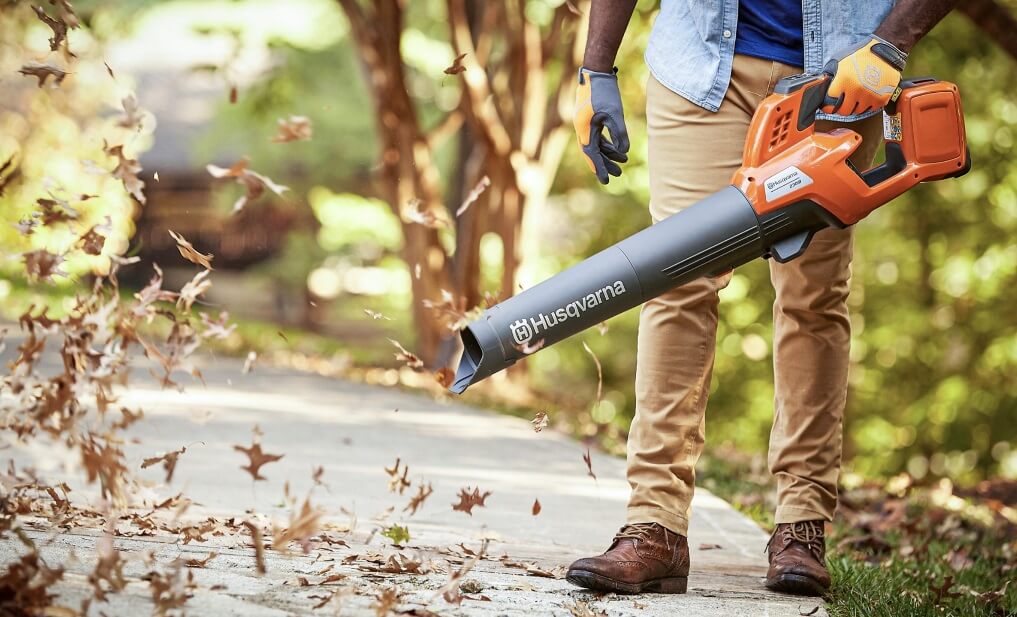 man walking on the road with a leaf blower in his hand